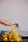 Кукурудзяна рука додає цукор до склянки лимонаду — стокове фото