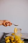 Mão de colheita adicionando açúcar em suco de citrinos frescos — Fotografia de Stock