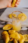 Cortar la mano exprimiendo jugo de limón en vidrio - foto de stock