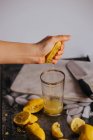 Crop fist juicing fresh lemon in glass — Stock Photo