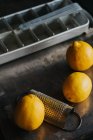 Vue rapprochée des citrons avec râpe par plateau de glace — Photo de stock