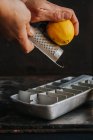 Coltivare le mani grattugiando scorza di limone in vaschetta di ghiaccio — Foto stock