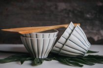 Still life of spatula and stacked tea bowls on leaf over grey — Stock Photo