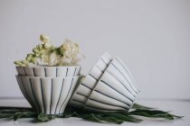 Bodegón de flores en tazones de té sobre hoja sobre gris - foto de stock