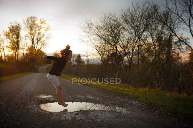 Menina pulando em poça — Fotografia de Stock