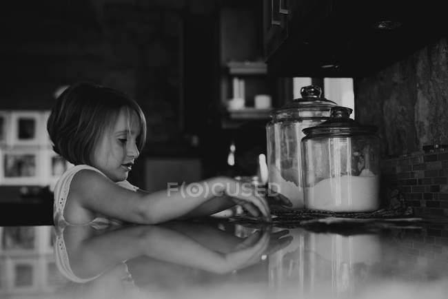 Chica joven mirando azúcar y harina - foto de stock