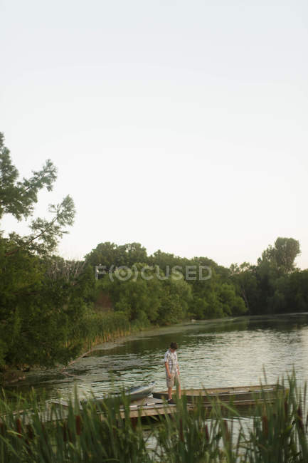 Garçon debout sur une jetée en bois — Photo de stock