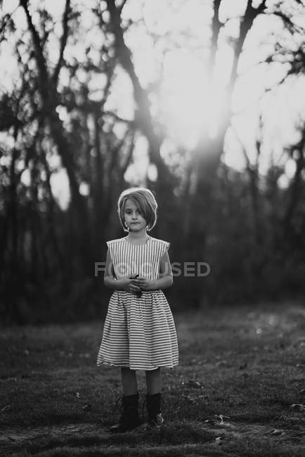 Aufrichtiges Mädchen posiert in Kleid und Stiefeln im Wald — Stockfoto