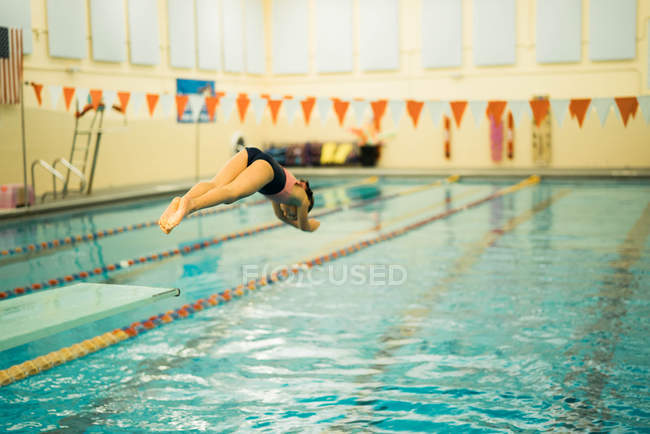 Chica joven saltando en la piscina - foto de stock