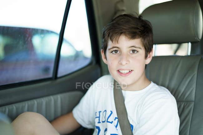 Niño sentado en el asiento trasero del coche - foto de stock