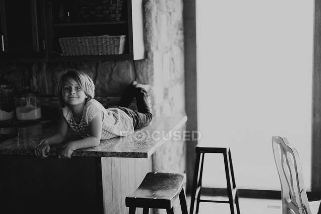Menina deitada na mesa na cozinha — Fotografia de Stock