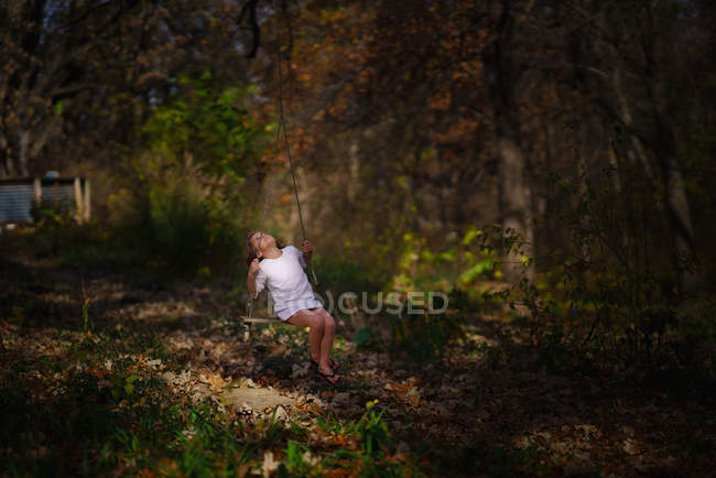 Fille sur swing dans automne forêt — Photo de stock