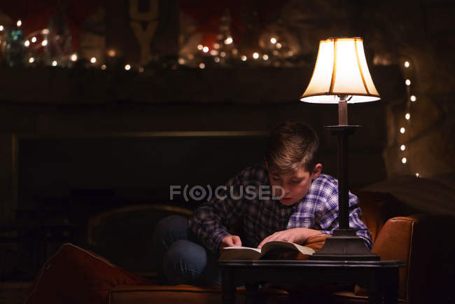 Boy reading book on coffee table — Stock Photo