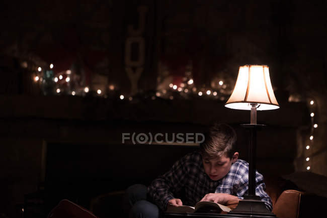 Мальчик читает книгу на кофейном столике — стоковое фото