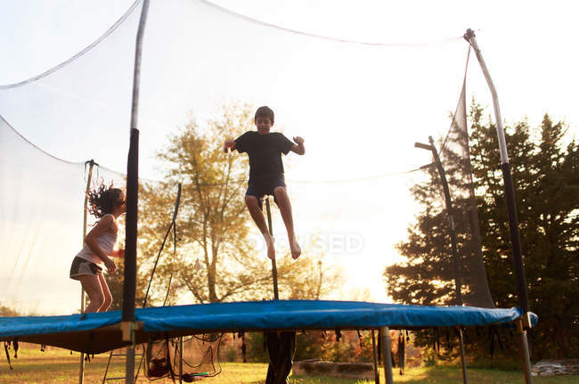 Двоє дітей стрибають на батуті — стокове фото