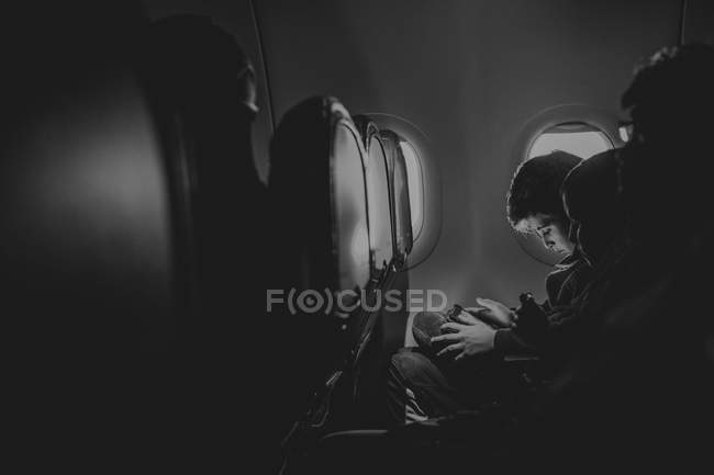 Мальчик с помощью цифрового устройства в самолете — стоковое фото