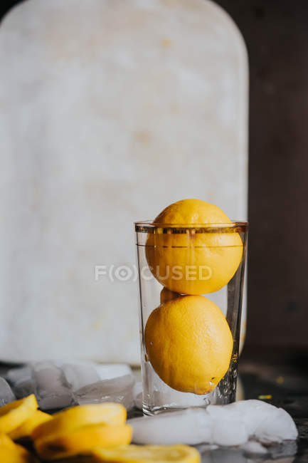 Fresh lemons in glass on table with ice — Stock Photo