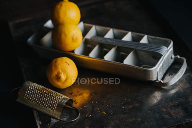 Bodegón de bandeja de hielo con limones y rallador - foto de stock