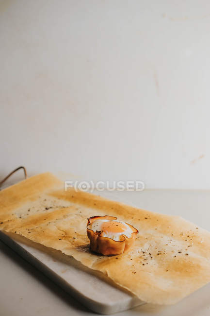 Запечений яєчний кошик на папері для випічки над мармуровими обробними дошками — стокове фото