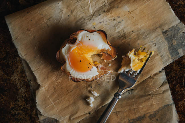 Cesta de huevo desgarrada sobre papel de hornear con tenedor - foto de stock