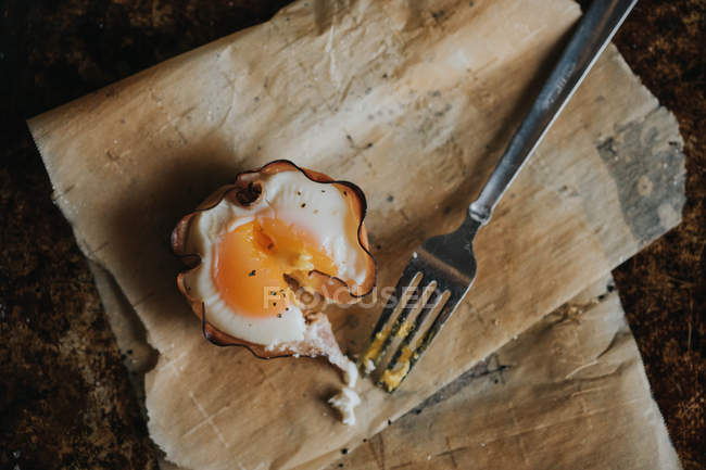 Безпосередньо над видом запеченого яєчного кошика та виделки на папері для випічки — стокове фото