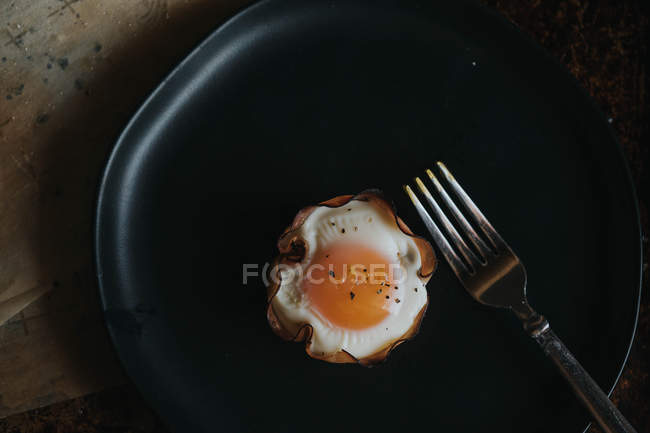 Прямо над видом на корзину для выпечки яиц на тарелке с вилкой — стоковое фото