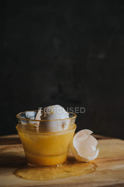 Cuenco de yemas rotas y claras de huevo con cáscaras de huevo sobre negro - foto de stock