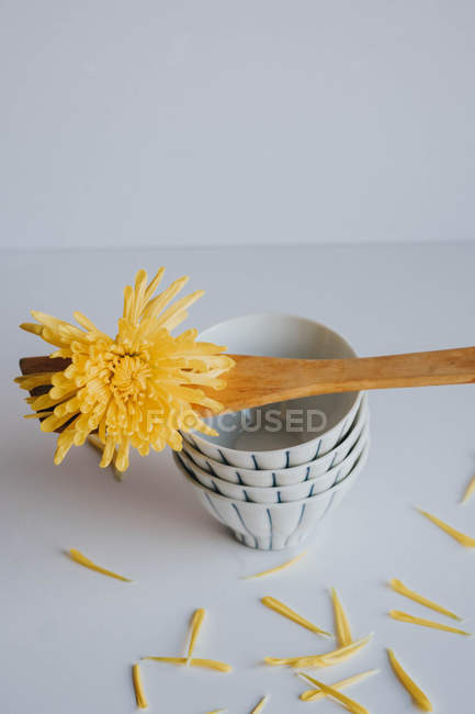 Flower head and spatula on stacked drinking bowls — Stock Photo