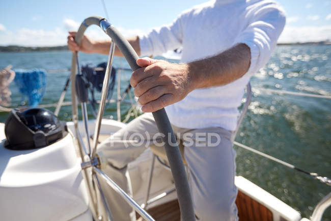 Uomo anziano al timone su barca o yacht a vela in mare — Foto stock