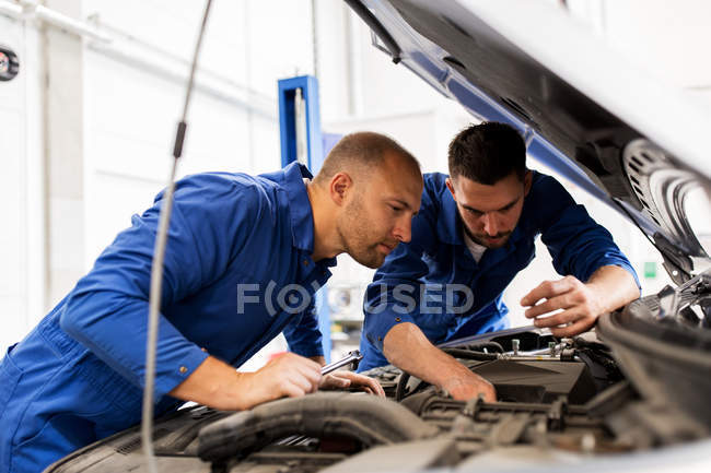 Mechanic men with wrench repairing car at workshop — Stock Photo