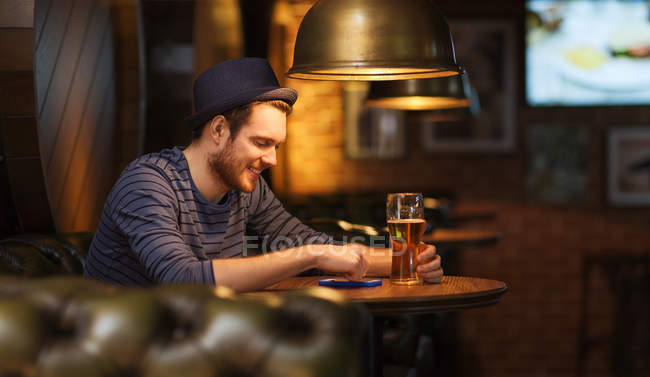 Uomo con smartphone e birra sms al bar — Foto stock