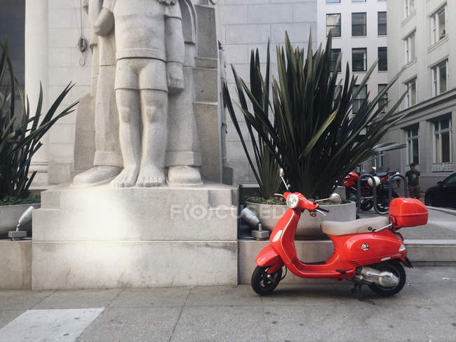 Red scooter on the sidewalk — Stock Photo