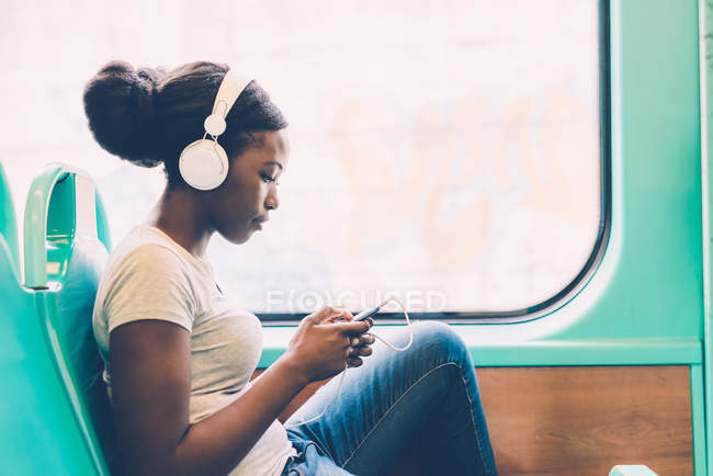 Mujer escuchando música viajando en autobús - foto de stock