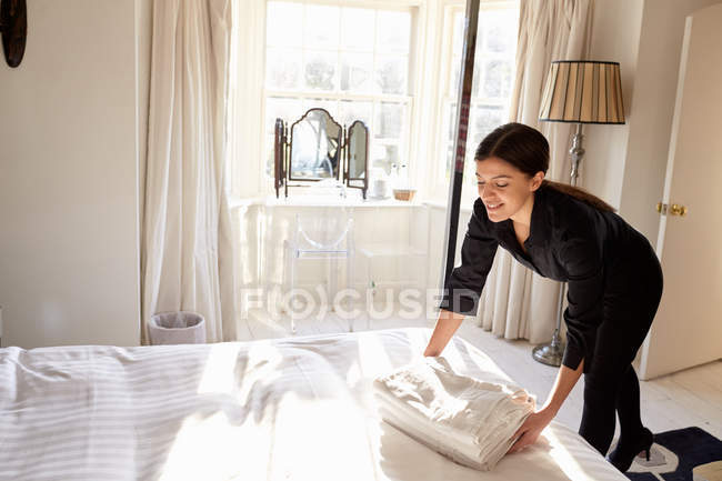 Zimmermädchen stellt frische Bettwäsche auf — Stockfoto