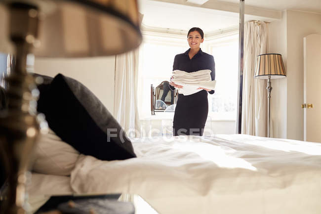 Zimmermädchen trägt Bettwäsche im Hotelzimmer — Stockfoto