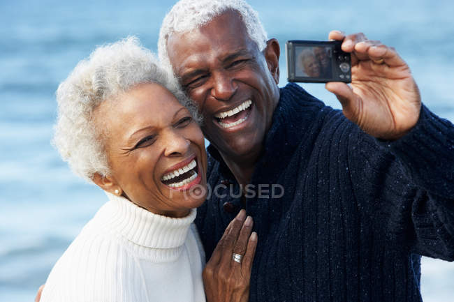 Seniorenpaar mit Kamera am Strand — Stockfoto