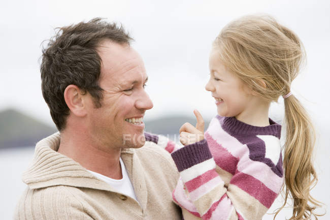 Padre e hija en la playa sonriendo - foto de stock