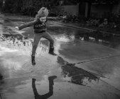Junge spritzt Wasser auf Straße — Stockfoto
