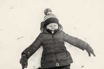 Sorrindo menina deitada na neve — Fotografia de Stock