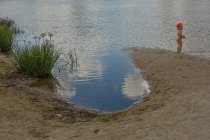 Chica de pie en la orilla del estanque - foto de stock