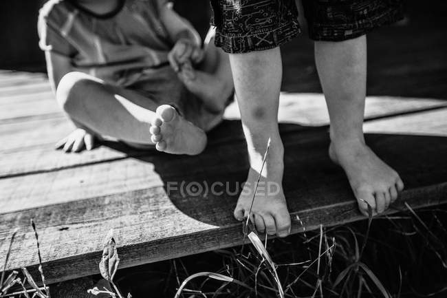 Niños piernas en terraza de madera - foto de stock