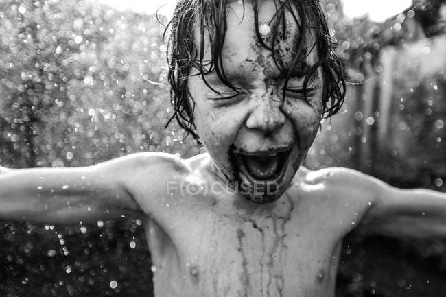Niño bajo salpicaduras de agua - foto de stock