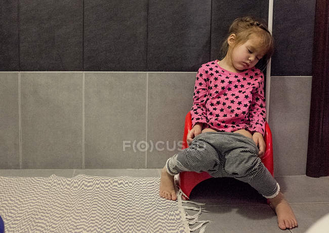 Chica sentada en el inodoro infantil - foto de stock