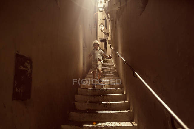 Niño caminando escaleras abajo - foto de stock