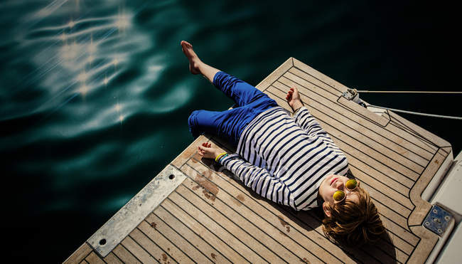 Мальчик лежит на деревянном пирсе — стоковое фото