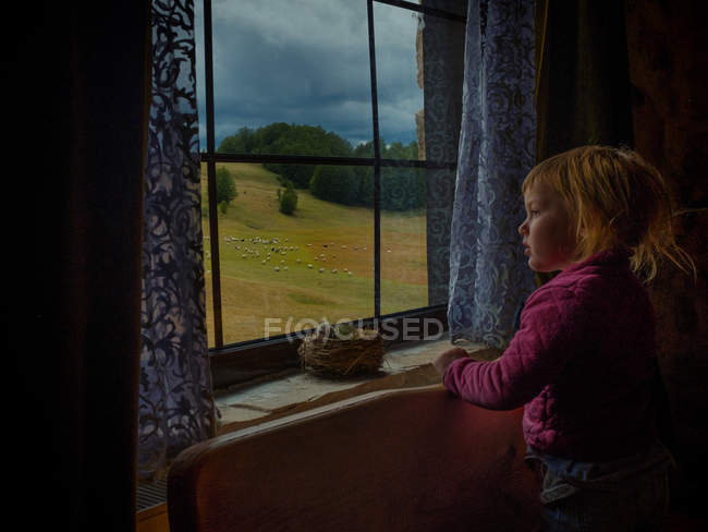 Mädchen schaut aus Fenster — Stockfoto
