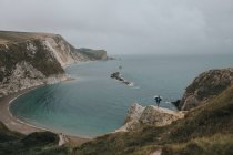 Байкер, що стоїть на скелі проти морського пейзажу — стокове фото