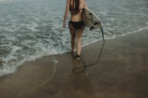 Дівчина з дошкою для серфінгу готова до серфінгу — стокове фото