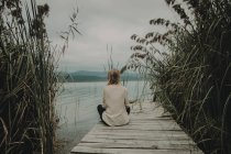 Девушка, сидящая на деревянной пристани — стоковое фото