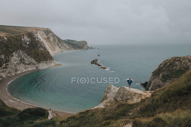 Байкер, що стоїть на скелі проти морського пейзажу — стокове фото
